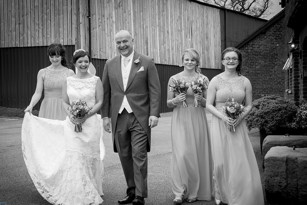 The bride and father of the bride prepare to walk down the aisle with bridesmaids