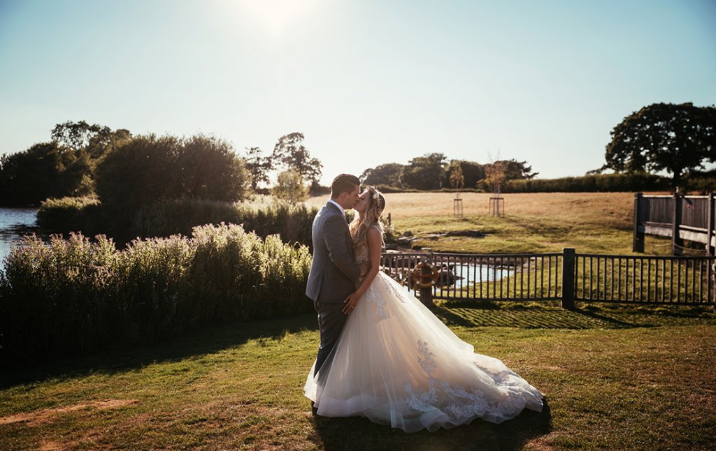 The happy newlyweds pose for a wedding photo as the sun sets at their summer wedding at Sandhole Oak Barn