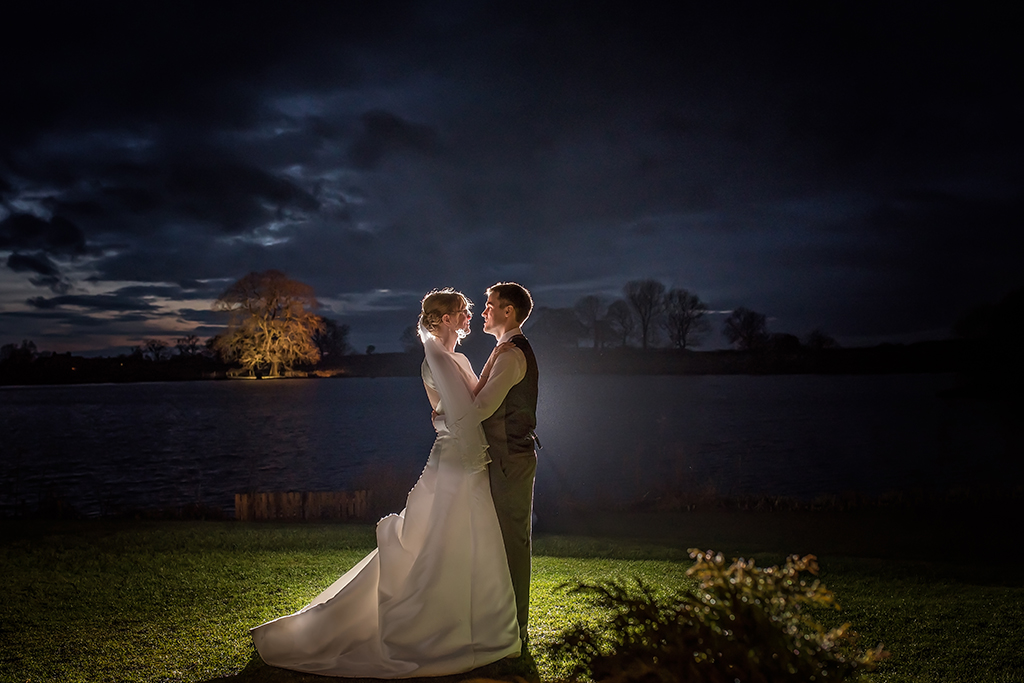 The happy newlyweds pose for some dramatic wedding photos by the lake at Sandhole Oak Barn
