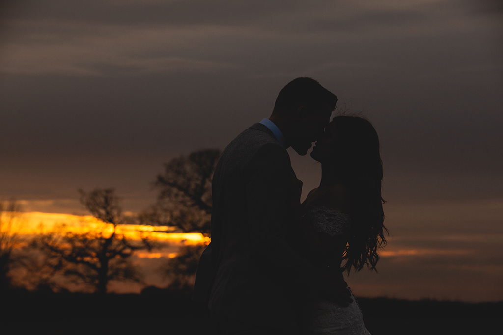 The bride and groom share a moment as they pose for a photo in the sunset at Sandhole Oak Barn in Cheshire