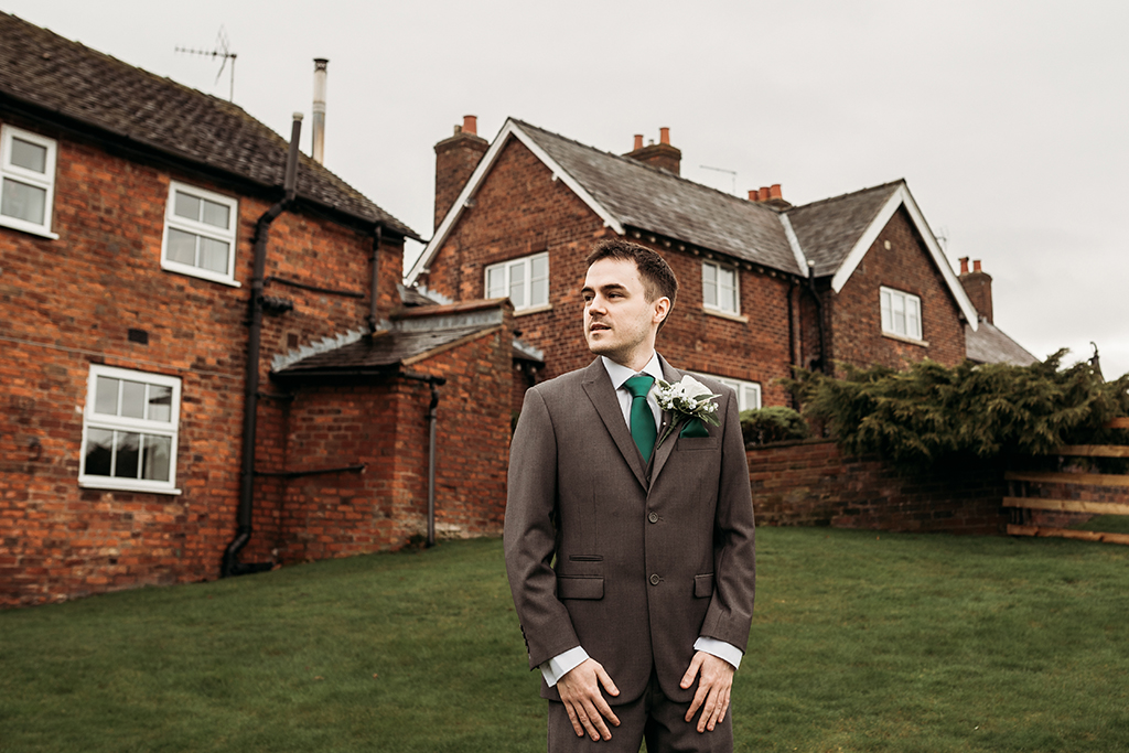 The groom looked the part wearing a grey-brown suit and green tie for his wedding at Sandhole Oak Barn in Cheshire