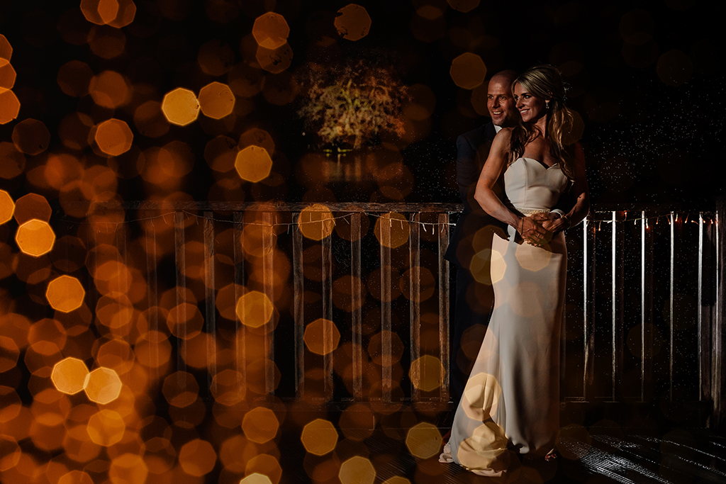 The happy couple pose for an evening wedding photo on the verandah at Sandhole Oak Barn