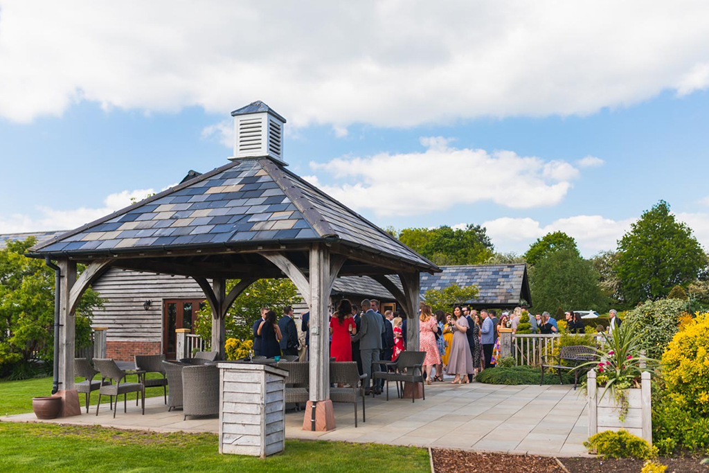 Wedding guests enjoy mingling under the Clock Tower at Sandhole Oak Barn in Cheshire