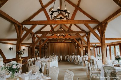 The tables were decorated with centrepieces of pale pink and white roses in vases and pretty hessian and lace sashes were tied to the chairs at this barn wedding.