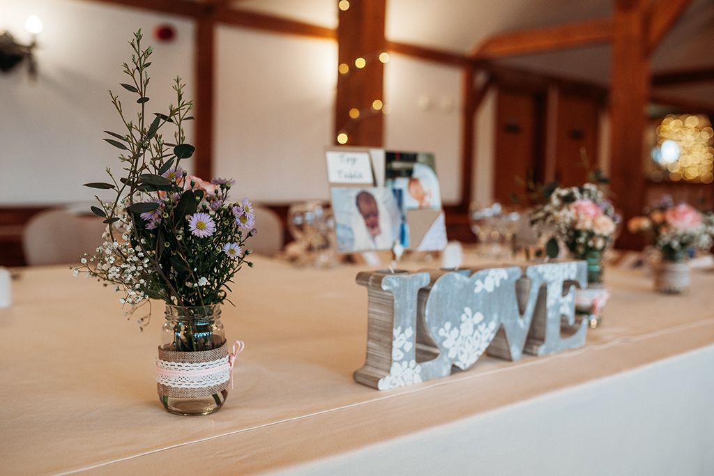The top table was decorated with jars of pretty wedding flowers at this spring wedding at Sandhole Oak Barn in Cheshire