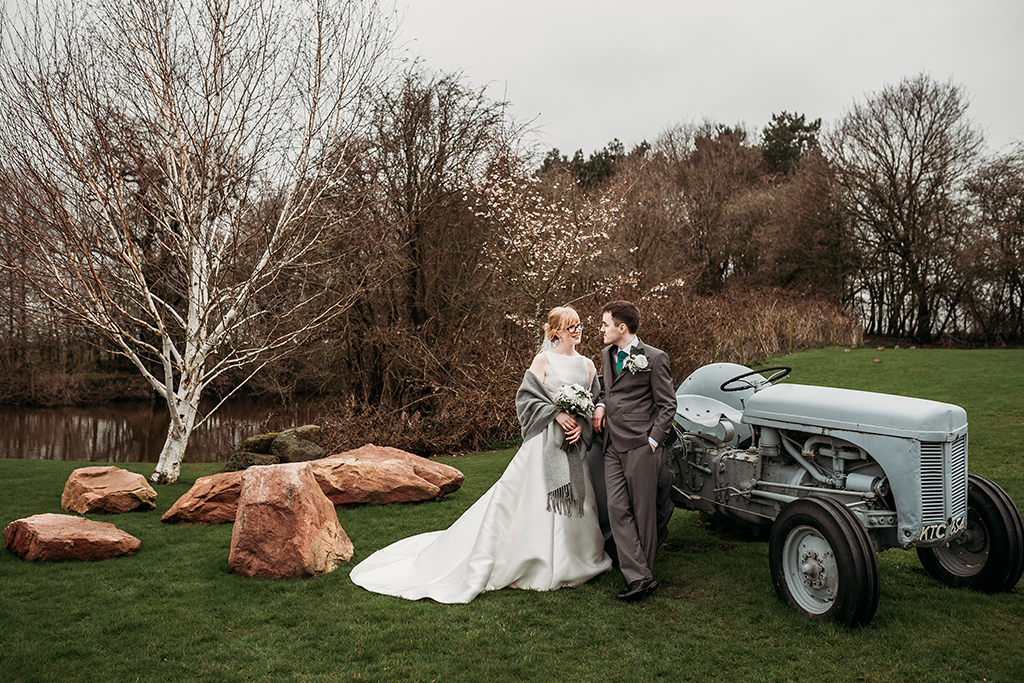 The happy newlyweds pose for wedding photos by the lake at this rural wedding venue in Cheshire 