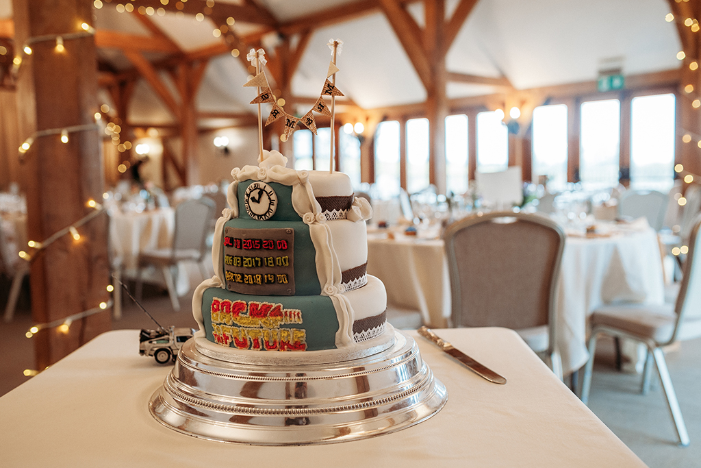 The wedding cake had a fun side and was decorated with a Back to The Future theme on one side at this wedding at Sandhole Oak Barn 