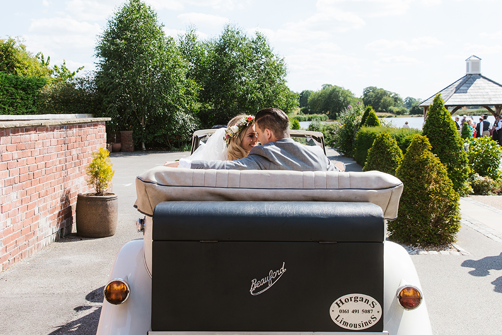 The happy newlyweds arrive to the wedding reception in style in a vintage wedding car at Sandhole Oak Barn