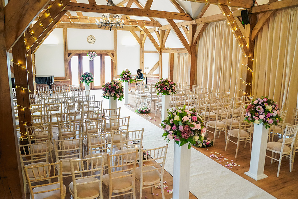 The ceremony room was dressed with pink wedding bouquets on pillars and fairy lights around the beams. 