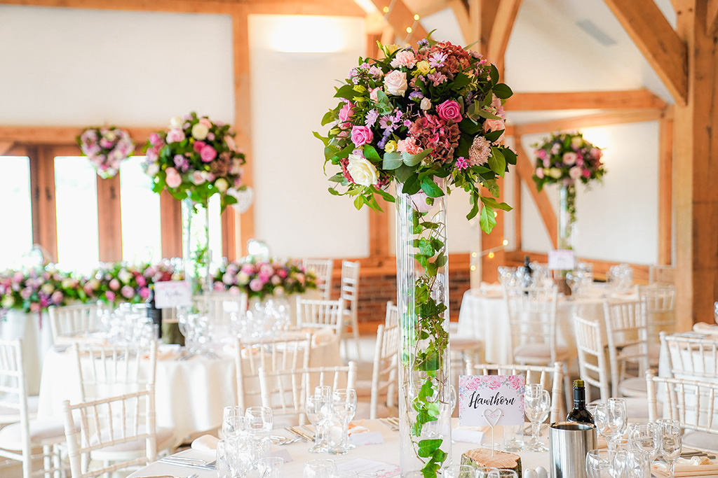 The tables were dressed with pretty pink bouquets on clear pillars at this barn venue in Cheshire 